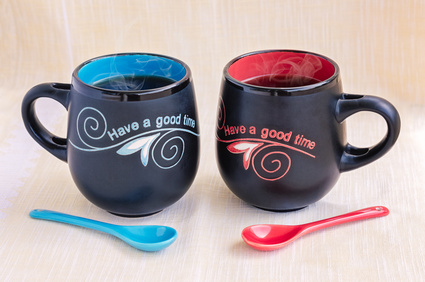 Red and Blue ceramic mugs of steaming tea with spoons and inscription.