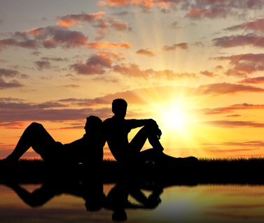 Concept of gay people. Silhouette of two gay holidaymakers near the river at sunset
